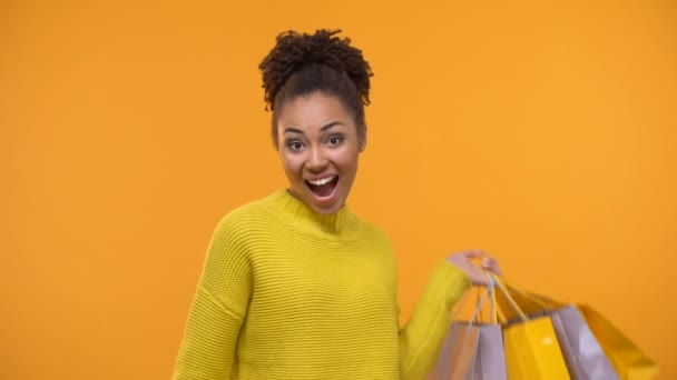 Emotional black lady holding bunch of dollars and shopping bags, cash back - Felvétel, videó