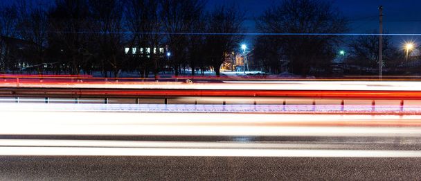 Pitkä valotus yöllä. Liikenne- ja autovalot paikalla. Elokuvallinen horisontaalinen laukaus
 - Valokuva, kuva