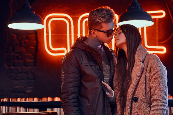 Пристрасна молода пара в стильному одязі цілується в кафе з промисловим інтер'єром
 - Фото, зображення