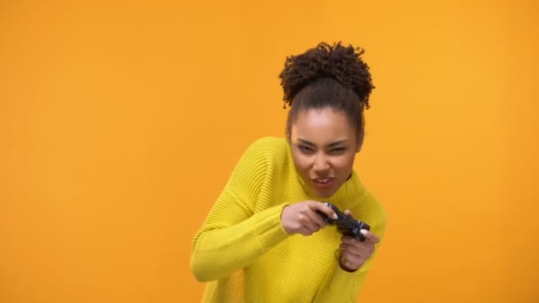 Young african american woman stoutly playing video games with game controller - Materiał filmowy, wideo