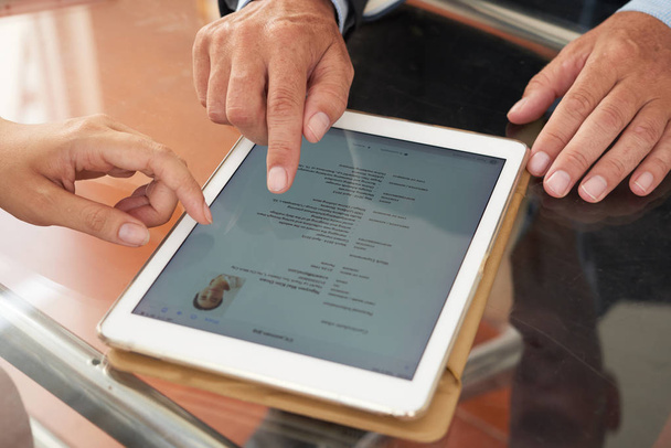 Gente de negocios viendo curriculum vitae en línea en la tableta PC en la mesa
 - Foto, imagen