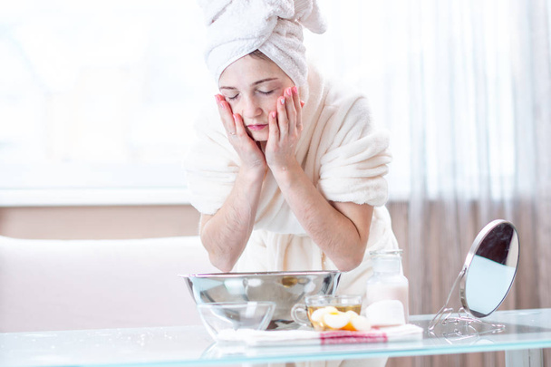 Krásná mladá žena s ručníkem na hlavě mytí její obličej vodou ráno. Koncepce hygieny a péče o pleť doma - Fotografie, Obrázek