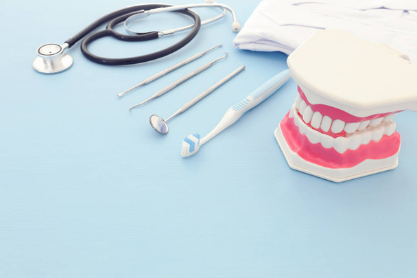 Ferramentas odontológicas usam para modelo de dentista e dentes plásticos na clínica. Fundo azul de madeira
 - Foto, Imagem