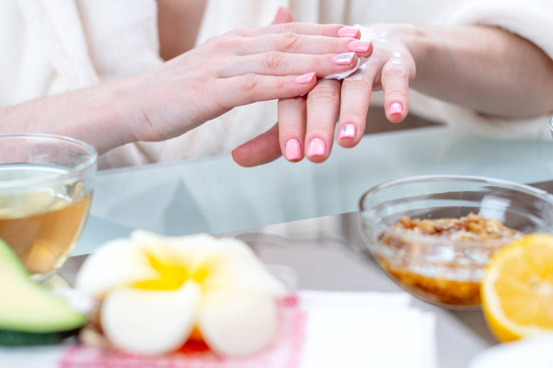 The woman applying the cream on her hands moisturizing and nourishing them with natural cosmetics close-up. Concept of hygiene and care for the skin - Photo, Image
