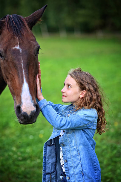 girl on the ranch is petting a horse - Φωτογραφία, εικόνα