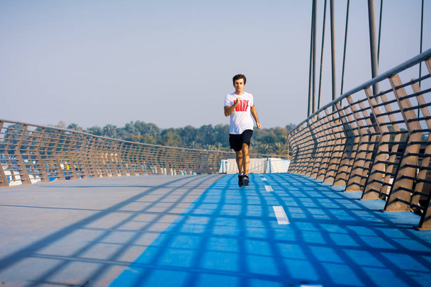 Człowiek działa na moście w słoneczny dzień, aktywny zdrowy tryb życia - Zdjęcie, obraz