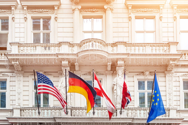 Национальные флаги на фасаде старого здания в европейском городе. Флаги США, Германии, Австрии, Европейского Союза и сброшенный флаг Великобритании. Концепция Брексита
. - Фото, изображение