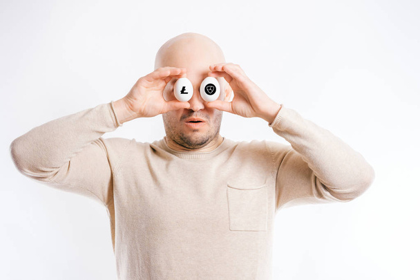 bald man covering eyes with chicken raw eggs - Foto, afbeelding