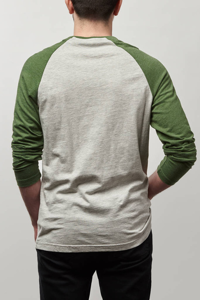 back view of man in raglan sleeve baseball shirt with copy space isolated on grey - 写真・画像