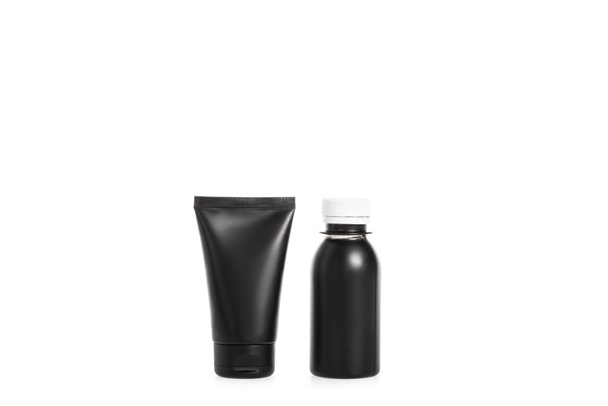 Estudio de tubo de crema negro y pequeña botella de plástico aislado en blanco
 - Foto, imagen