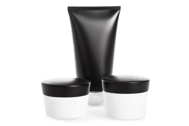 Studio shot van crème tube en containers geïsoleerd op wit - Foto, afbeelding