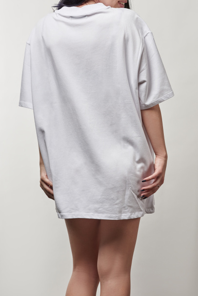 back view of young woman in white oversize t-shirt with copy space isolated on grey - Zdjęcie, obraz