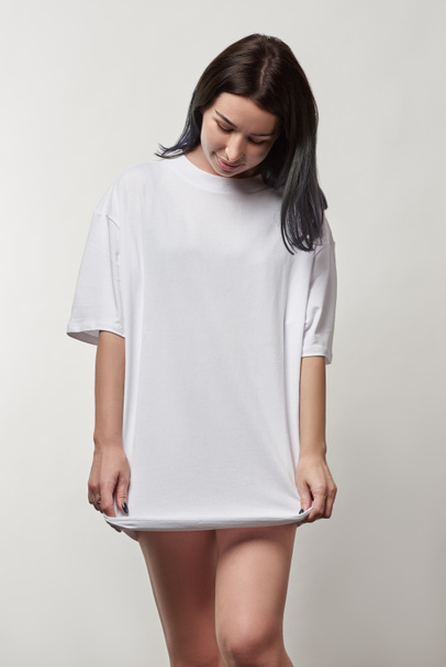 beautiful young woman in white oversize t-shirt with copy space isolated on grey - Photo, Image