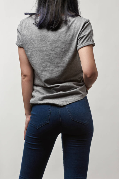 Widok z młoda kobieta w denim tyłu i szary t-shirt z kopia miejsce na białym tle - Zdjęcie, obraz