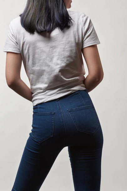 vista posterior de mujer joven en mezclilla y camiseta blanca con espacio de copia aislado en blanco
 - Foto, Imagen