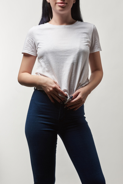 обрезанный вид молодой женщины в белой футболке с копировальным пространством, изолированным на сером
 - Фото, изображение