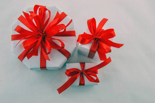 Κουτιά δώρου, σε ολόλευκο με κόκκινα διακοσμητικά κορδέλες, απομονώνονται σε λευκό φόντο. - Φωτογραφία, εικόνα