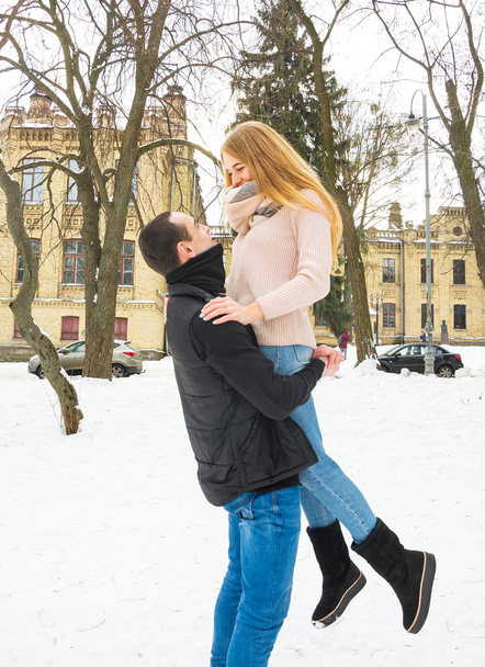Una pareja cariñosa en invierno. El tipo levanta a una chica en sus brazos en la calle en invierno. Día de San Valentín
 - Foto, Imagen