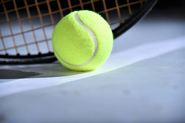 tennis ball with racket  lay on gray color court - Foto, afbeelding