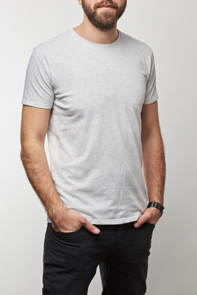 cropped view of man with hands in pockets in white t-shirt with copy space isolated on grey - Photo, Image