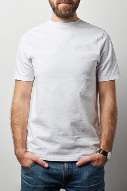cropped view of man with hands in pockets in white t-shirt with copy space isolated on grey - Photo, Image