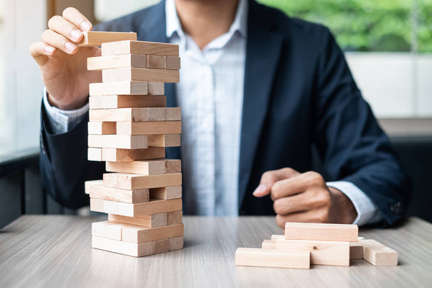 Businessman hand placing or pulling wooden block on the tower. Business planning, Risk Management, Solution and strategy Concepts - Valokuva, kuva