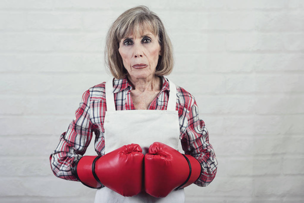smutny starszy kobieta z rękawice bokserskie na tle Cegła - Zdjęcie, obraz