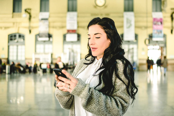 Piękne dojrzałe kobiety sprawdzając harmonogramy jej pociąg na jej telefon komórkowy. - Zdjęcie, obraz