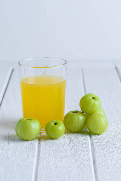 Indian gooseberry and juice on white wooden table - Foto, afbeelding