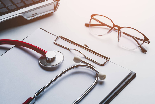 stethoscope and glasses on laptop with clipboard blank paper doctor online, medical concept - 写真・画像