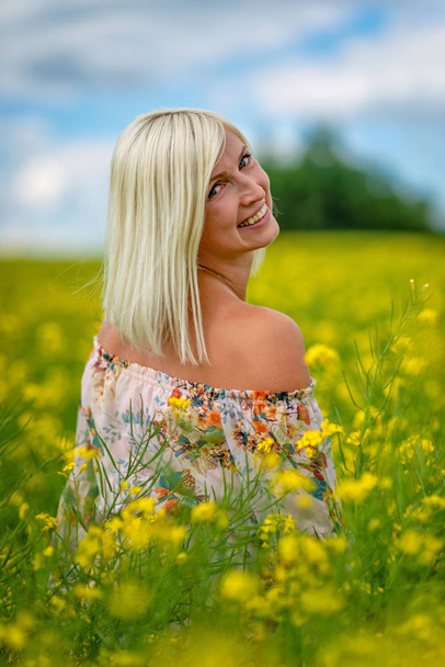 Soft, selective focus. Beautiful, attractive, blond woman in a yellow flower meadow. - Foto, Bild