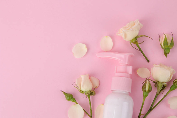 cosmetics for face and body in pink bottles with fresh roses on a delicate pink background. view from above. space for text - Fotografie, Obrázek