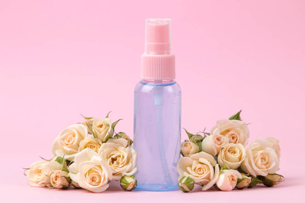 cosméticos para la cara y el cuerpo en botellas de color rosa con rosas frescas sobre un delicado fondo rosa. crema y loción. spa
. - Foto, Imagen
