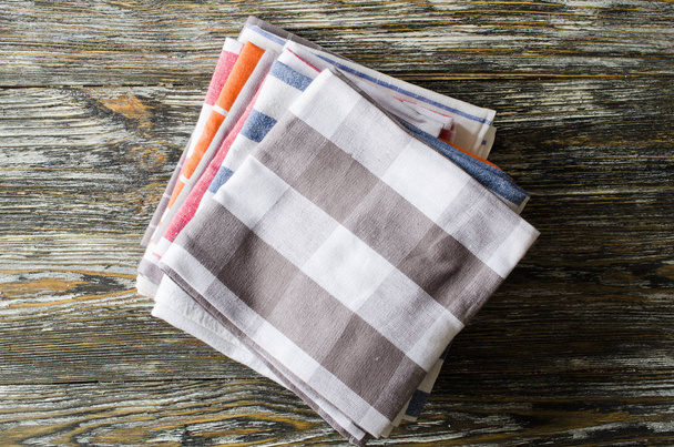 Stack of kitchen towels or napkins over the rustic wooden table. View from above with copy space - Photo, Image