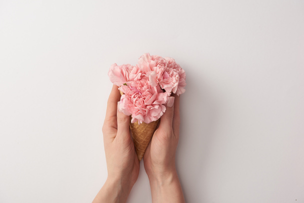 cropped shot of woman holding wafer cone with beautiful tender flowers isolated on grey  - Photo, Image