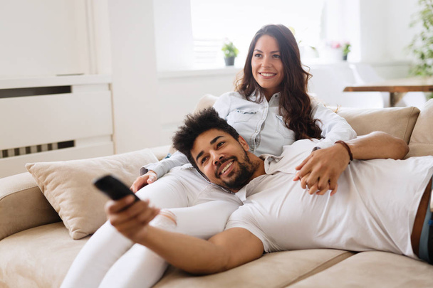 Happy couple in love lying on sofa together and relaxing at home - Zdjęcie, obraz