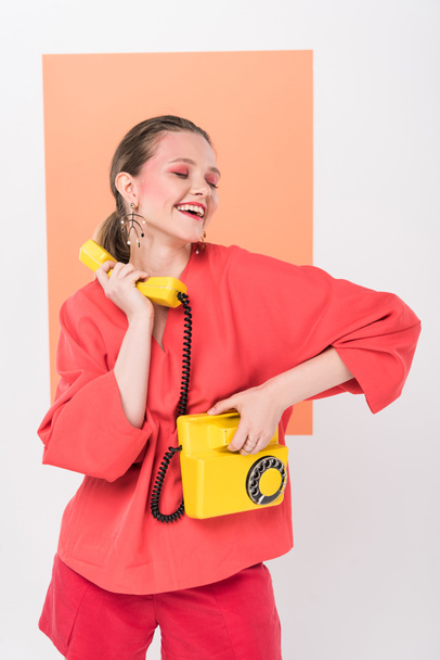 happy stylish girl holding retro telephone and posing with living coral on background - Photo, Image