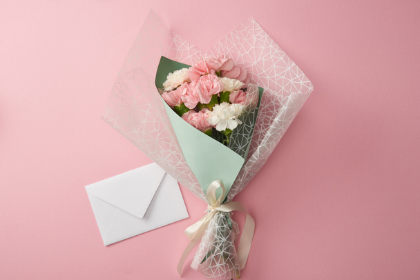 güzel ihale çiçek buketi ve beyaz zarfın üzerinde pembe izole üstten görünüm  - Fotoğraf, Görsel