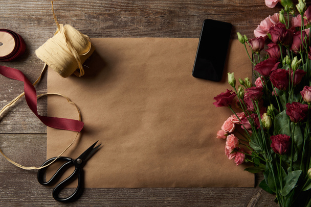 pohled shora z krásných různé květiny, smartphone s prázdnou obrazovkou, nůžky a stuhy na kraftový papír  - Fotografie, Obrázek