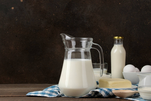 milk products. Milk, sour cream, cheese, butter and cottage cheese on a brown wooden table. space for text - Photo, Image