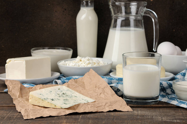 молочные продукты. молоко, сметана, сыр, масло и творог на коричневом деревянном столе
 - Фото, изображение