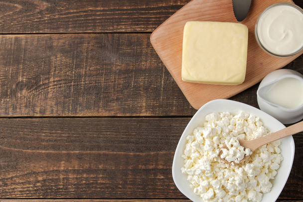 produtos lácteos. Leite, creme de leite, queijo, manteiga e queijo cottage em uma mesa de madeira marrom. vista superior. moldura. espaço para texto
 - Foto, Imagem