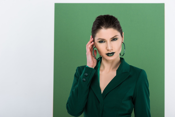 beautiful fashionable woman in formal wear looking at camera and posing with sea green on background - Photo, Image