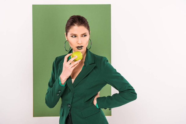 beautiful stylish woman holding apple and posing with sea green on background - Foto, imagen