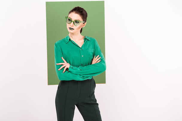 beautiful fashionable woman in sunglasses posing and looking away with sea green on background - Фото, изображение