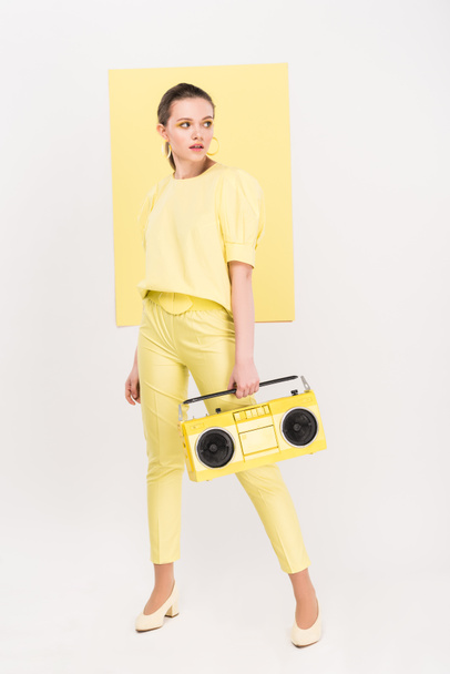 stylish girl holding retro boombox, looking away and posing with limelight on background - Foto, afbeelding