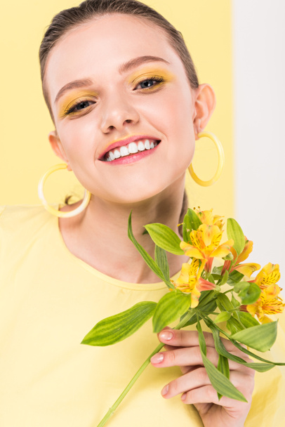 smiling stylish girl with flowers looking at camera with limelight on background - Fotoğraf, Görsel