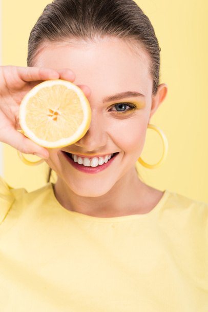 beautiful stylish girl holding lemon, smiling and looking at camera isolated on limelight - Photo, Image