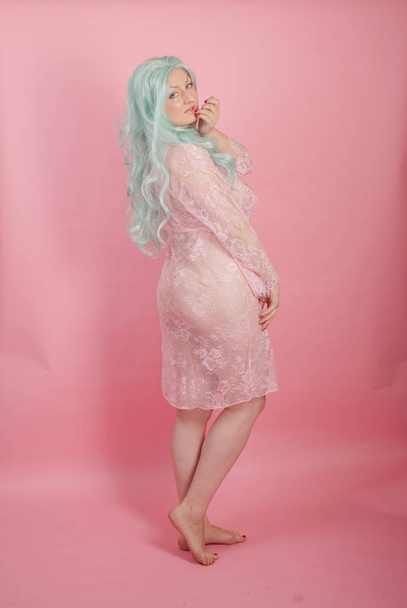 kanyargós pufók szexi felnőtt nő pózol meztelenül, egyedül a rózsaszín stúdió háttere átlátszó aranyos ruhák - Fotó, kép