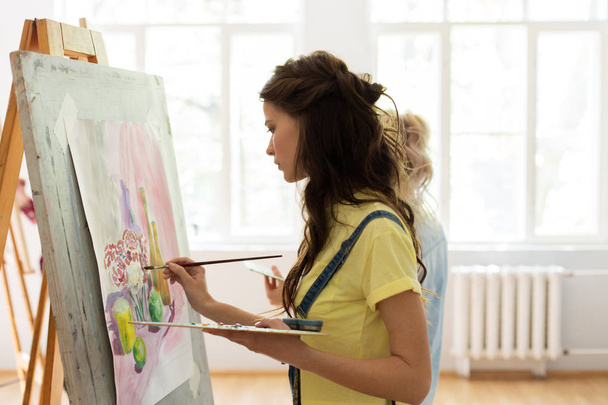 woman with easel painting at art school studio - Photo, image